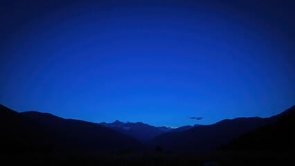 A majestic blue sky ablaze with vibrant, glowing rings that burst outward like divine fireworks, set against the rugged majesty of distant mountains