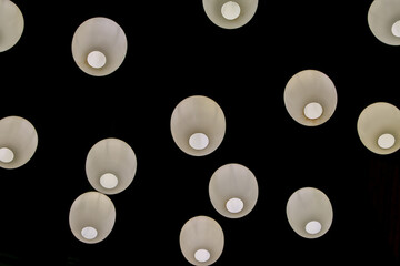 This abstract scene is with white pendants, balls, hanging from a dark ceiling