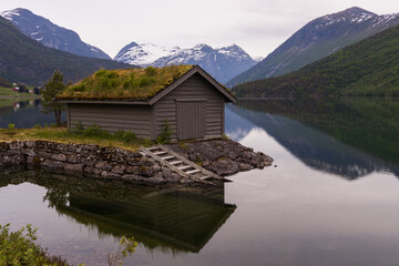 Fototapeta premium Bootshaus am Fjord mit schneebedeckten Bergen in Norwegen im Herbst.