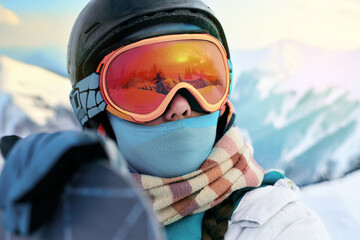 A snowboarder dressed in full winter attire with reflective goggles enjoys a scenic mountain view
