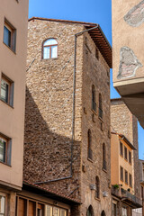 The charming streets of Florence, the unique stone buildings and architectural details under the bright blue sky, capturing the essence of Tuscany.