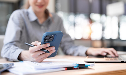 Fototapeta premium Woman using smartphone during working at office with digital tablet on table, social network. Close up, business woman using mobile smart phone