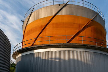 Natural, biogas storage container under a blue and lightly clouded sky.