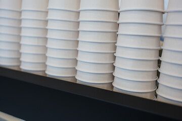 The stack of white paper cups on the coffee machine