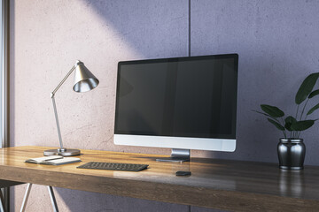 Desk setup with computer monitor, lamp, keyboard, notebook, and plant on wooden table near concrete wall in modern interior room. 3D Rendering