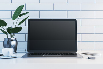 Fototapeta premium Minimalist workspace with laptop, cup, plant, and smartphone on white desk against white brick wall. 3D Rendering