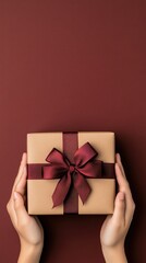 Woman s hands present a beautifully wrapped gift box with a red ribbon bow on a vibrant green surface, ideal for celebrations