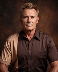 Obraz premium A serious portrait of a mature man with stylish hair, wearing a two-tone brown shirt against a textured dark background.