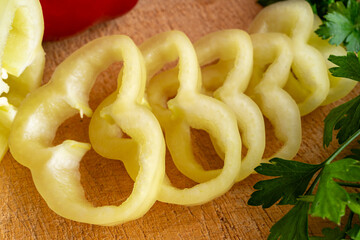 Sliced yellow bell pepper rings arranged on a wooden cutting board