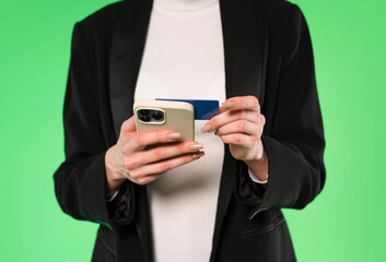 Person using smartphone and credit card for online shopping against a green background