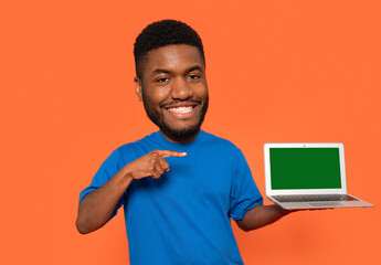 Happy person showcasing a laptop with a blank screen against an orange background