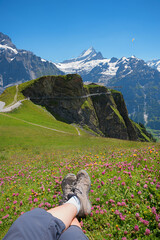 woman relaxing at flower meadow with view to adventurous walk along Grindelwald cliff walk.