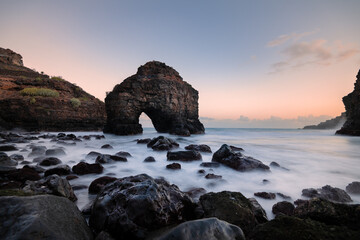 Ocean landscape with coastal rock arch at sunset