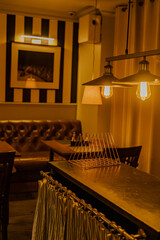 Stylish lighting lamps over a bar counter, a cozy corner of a restaurant bathed in warm, inviting...