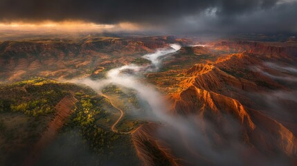 Naklejka premium Aerial view of a canyon landscape with fog and dramatic lighting.