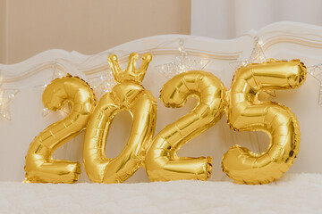 Golden inflatable numbers 2025 on the bed in the bedroom.