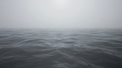 Obraz premium Calm, gray ocean water under a foggy sky.