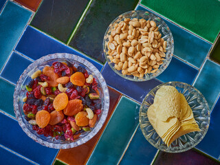Healthy nut and fruit snack with peanuts amd crisps in glass bowls