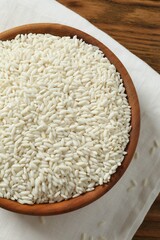 Healthy eating. Wooden bowl with uncooked rice on a wooden background