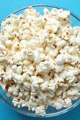 Delicious popcorn in a bowl on a colored background