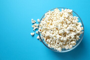 Delicious popcorn in a bowl on a colored background