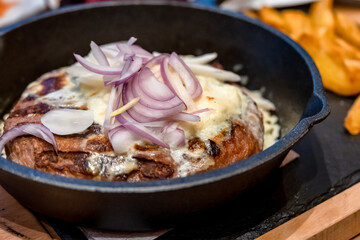 Onion Burger. Meat burger of ground meat fried in oil on a frying pan with three types of onions, close up