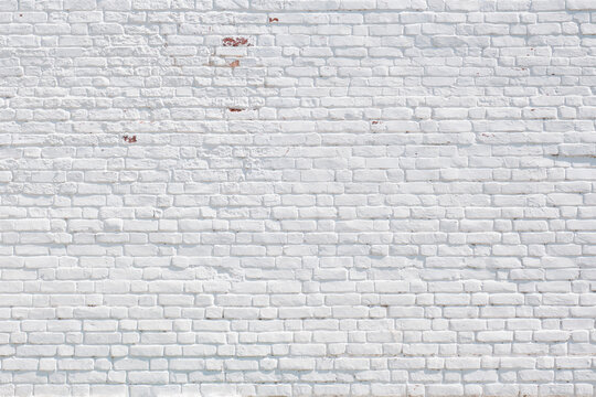 Old white painted brick wall of 18th century as historical textured background.