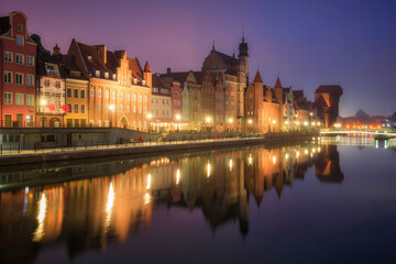 Naklejka premium Beautiful architecture of the old town in Gdansk by the Motława river with a historic port crane at wintery night. Poland