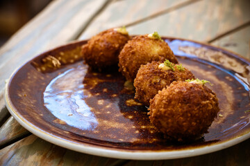 Close-Up of Crispy Croquettes on a Rustic Plate.  Four golden-brown croquettes served on a rustic plate, garnished and ready to enjoy as a delicious appetizer.