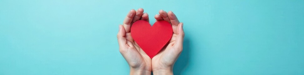 Fototapeta premium Top view of red heart held by hand on baby blue background, charity concept, giving, volunteer