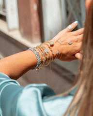 A stylish woman adorned with layered gold and diamond jewelry, 
including necklaces, bracelets, rings.