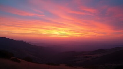 Obraz premium Serene Sunset Panorama, Vibrant Sky over Rolling Hills and Distant Mountains