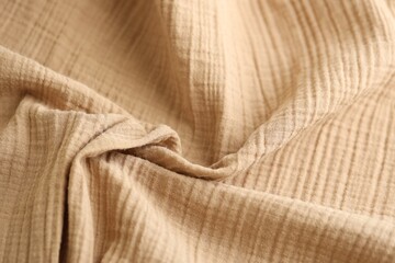 Texture of crumpled linen fabric under natural light in peach fuzz color