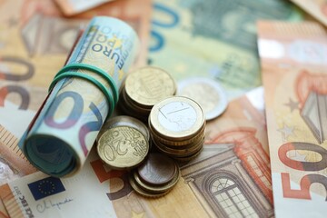 Roll of euro currency money bills and many euro cents on banknotes of european union