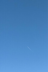 Jet airplane is flying with white contrail passing through the cloud on blue sky background