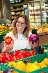 A woman in her 30s-40s selects fresh fruits and vegetables in a supermarket. The photo emphasizes organic food, healthy eating, vegan lifestyle, sustainable living, and mindful nutrition choices.