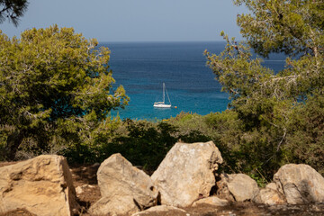 Rocky Coastline with Sailboat in the Azure Sea