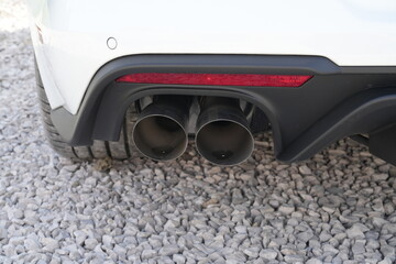 Na zdjęciu widoczny jest tył samochodu, a dokładniej fragment zderzaka wraz z podw&oacute;jną końc&oacute;wką układu wydechowego. Auto stoi na podłożu z jasnych kamyk&oacute;w, a obok widać tylną oponę pojazdu.