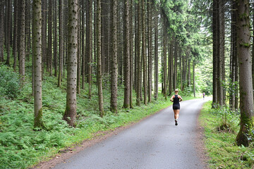 Obraz premium Woman jogging along a peaceful forest road