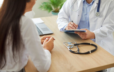 Close up shot of a doctor or nurse writing a prescription for the patient during a medical...