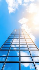 Obraz premium Imposing Urban Skyscraper Reaching Towards Bright Blue Sky with Fluffy White Clouds Creating a Dynamic and Inspiring Cityscape Atmosphere