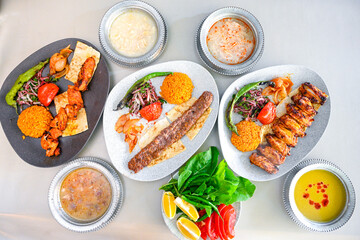 Delicious meat kebab with fresh vegetable salad served with variety of Turkish dishes and appetizers. Top view of assorted Turkish food and meze, tasty and healthy Mediterranean cuisine.