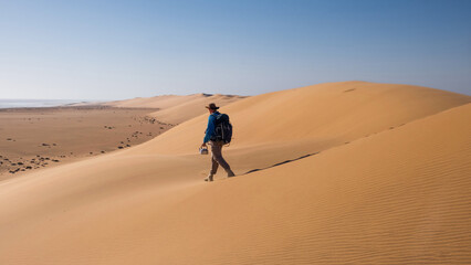 A male tourist walks with a kettle of water through the Namibian desert