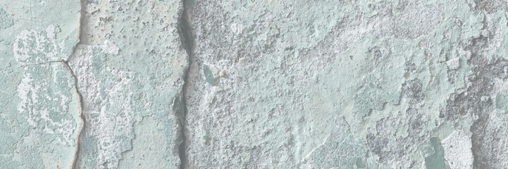 Green peeling paint on the wall. Old concrete wall with cracked flaking paint. Weathered rough painted surface with patterns of cracks and peeling. High resolution texture for background and design.