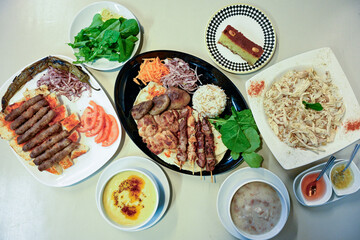 Delicious meat kebab with fresh vegetable salad served with variety of Turkish dishes and appetizers. Top view of assorted Turkish food and meze, tasty and healthy Mediterranean cuisine.