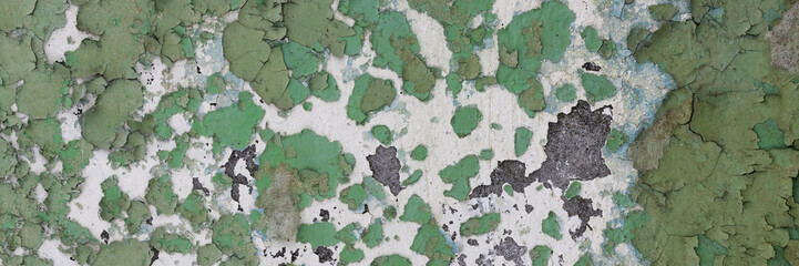 Peeling paint on the wall. Panorama of a concrete wall with old cracked flaking paint. Weathered rough painted surface with patterns of cracks and peeling. Wide panoramic texture for grunge background