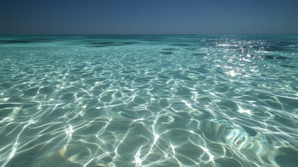 A beautiful view of the sparkling clear ocean water. The sunlight dances on the surface, creating a serene and peaceful ocean landscape for relaxation and enjoyment.