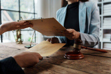 Lawyer and client exchanging documents in a legal office, with a gavel and themis statue in the background