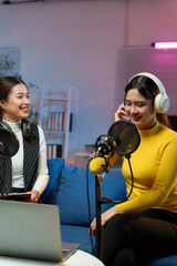 Two content creators recording audio podcast using professional microphone and headphones in home...