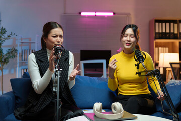 Two content creators recording their audio show using professional microphones and headphones in a...